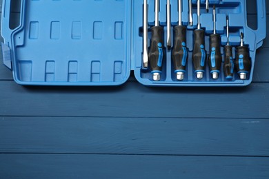 Photo of Set of screwdrivers in open toolbox on blue wooden table, top view. Space for text