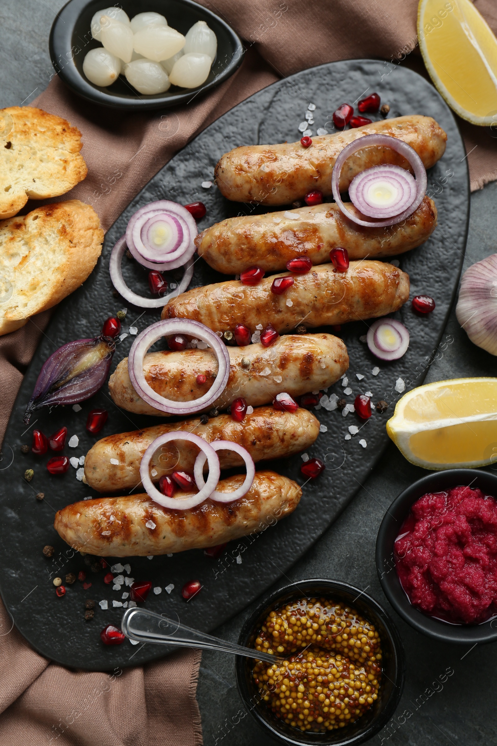 Photo of Tasty grilled sausages served on grey table, flat lay