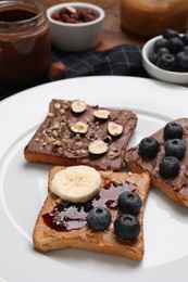 Different tasty toasts with nut butter and products on table, closeup