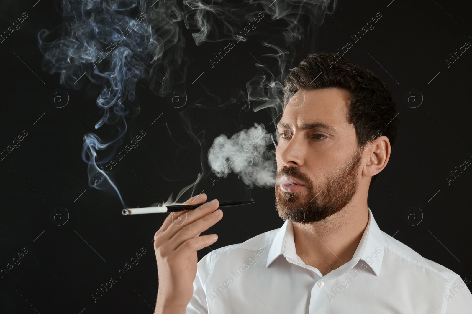 Photo of Man using long cigarette holder for smoking on black background