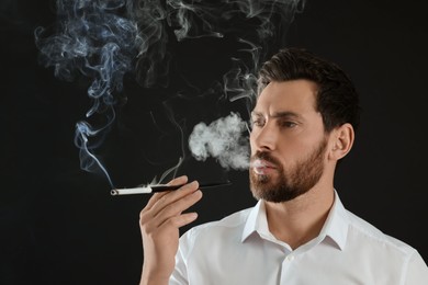 Man using long cigarette holder for smoking on black background