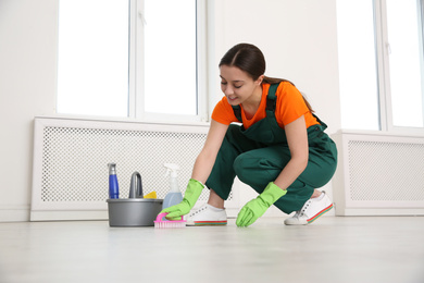 Photo of Professional young janitor polishing floor indoors. Cleaning service