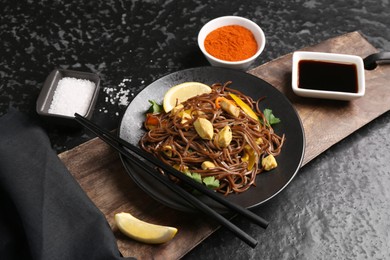 Photo of Stir-fry. Tasty noodles with vegetables and meat served on dark textured table