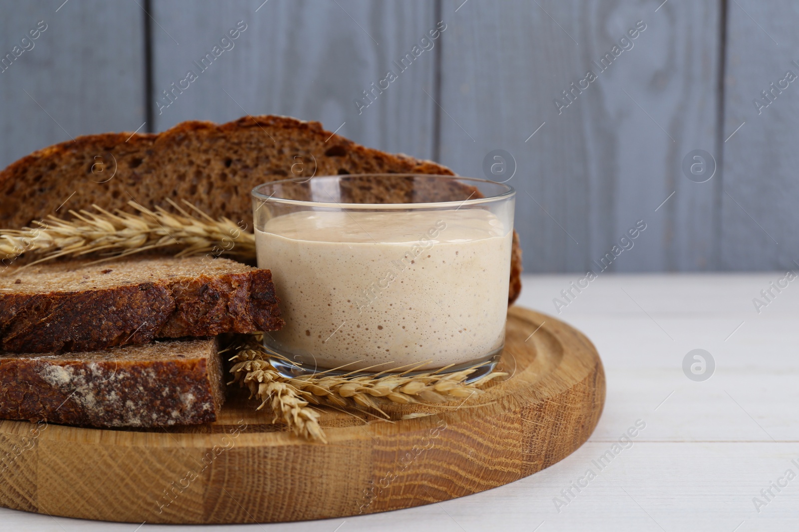 Photo of Freshly baked bread, sourdough and spikes on white wooden table. Space for text