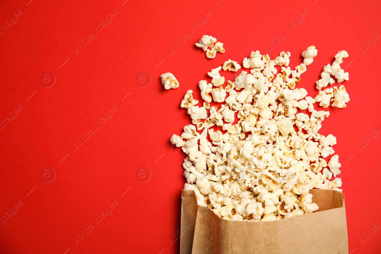 Photo of Paper bag with tasty fresh popcorn on color background, top view