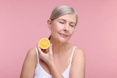 Photo of Beautiful woman with half of orange rich in vitamin C on pink background