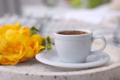 Photo of Cup of morning coffee and flowers on tray indoors, closeup