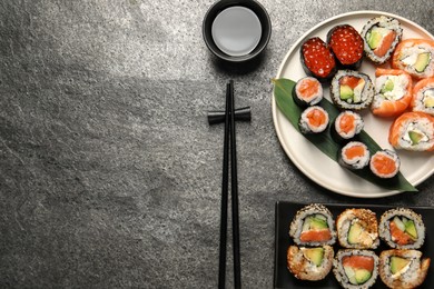 Photo of Delicious sushi rolls on dark grey table, flat lay. Space for text