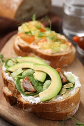 Photo of Tasty vegan sandwiches with vegetables on wooden board, closeup