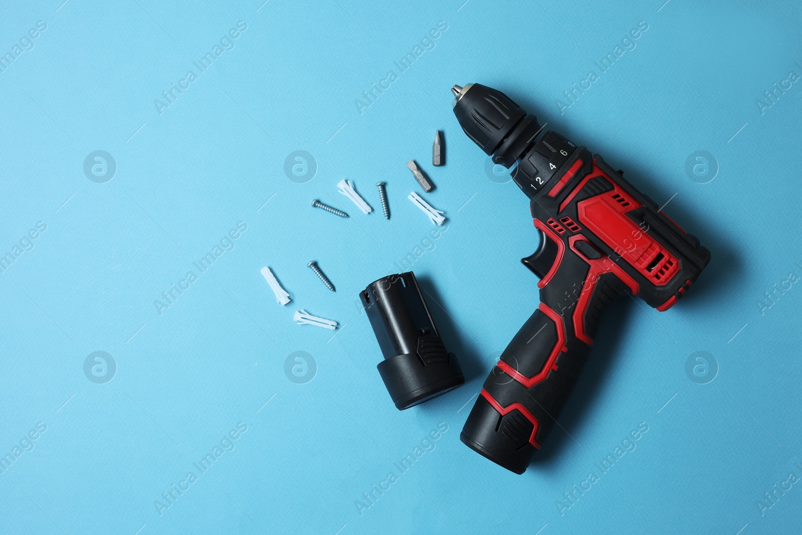Photo of Electric screwdriver and accessories on light blue background, flat lay. Space for text