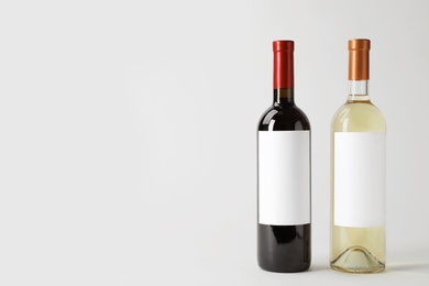 Photo of Bottles of delicious wines with blank labels on white background