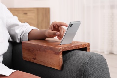 Photo of Man using smartphone on sofa armrest wooden table at home, closeup