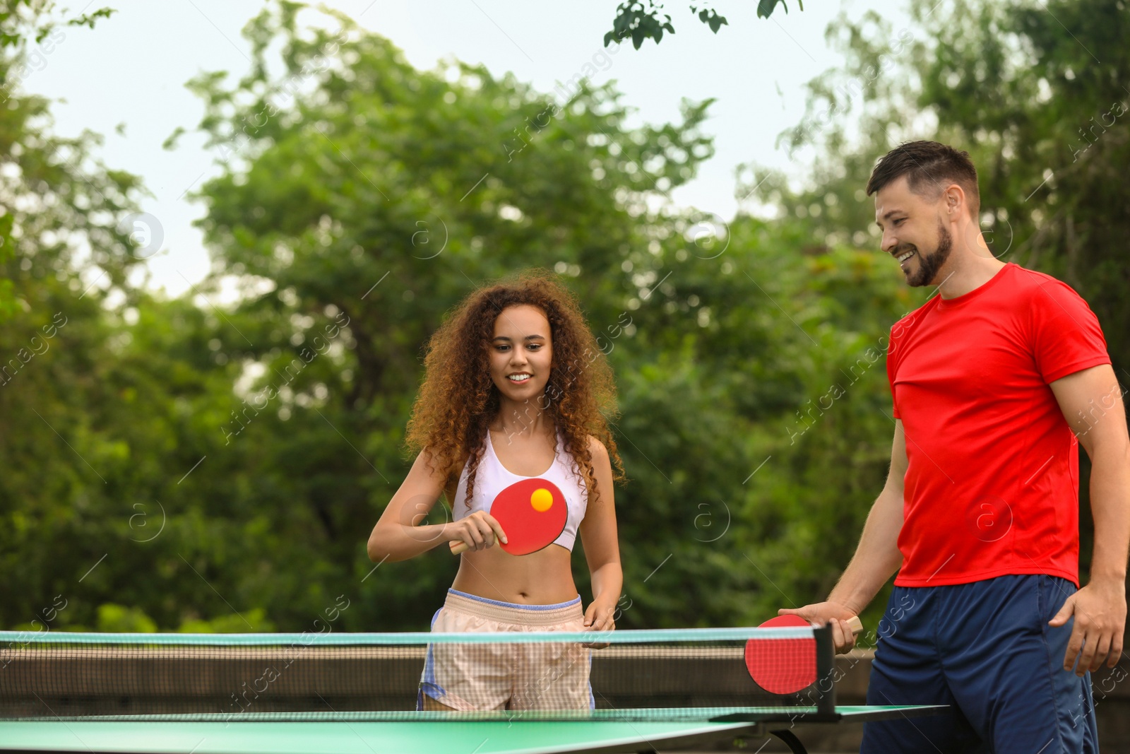 Photo of Friends playing ping pong outdoors on summer day