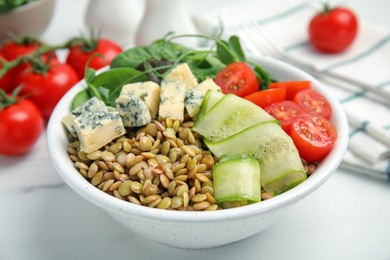 Photo of Delicious lentil bowl with blue cheese, tomatoes and cucumber on white marble table