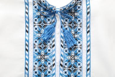 Photo of Beautiful white shirt with light blue Ukrainian national embroidery, top view