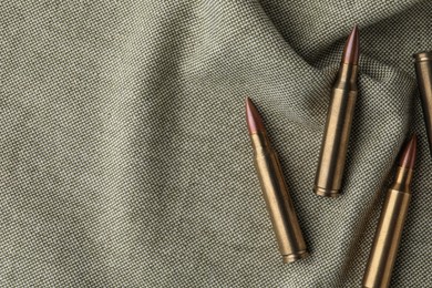 Photo of Many brass bullets on burlap, flat lay. Space for text