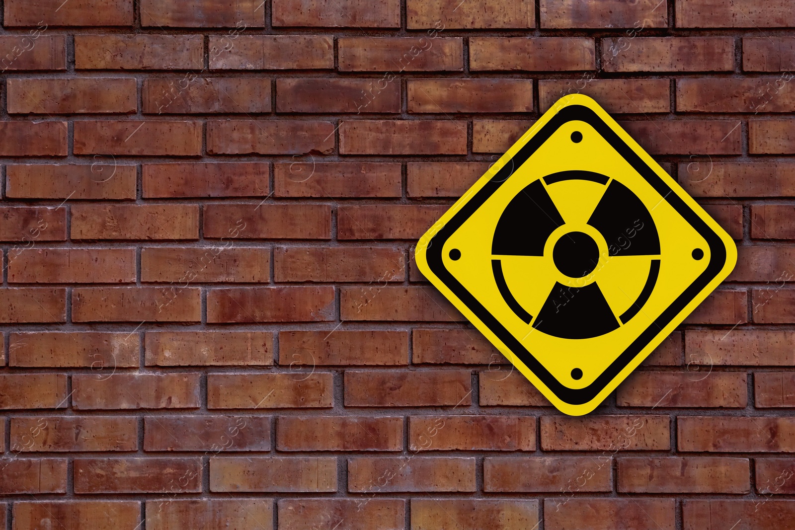 Image of Radioactive sign on brick wall, space for text. Hazard symbol