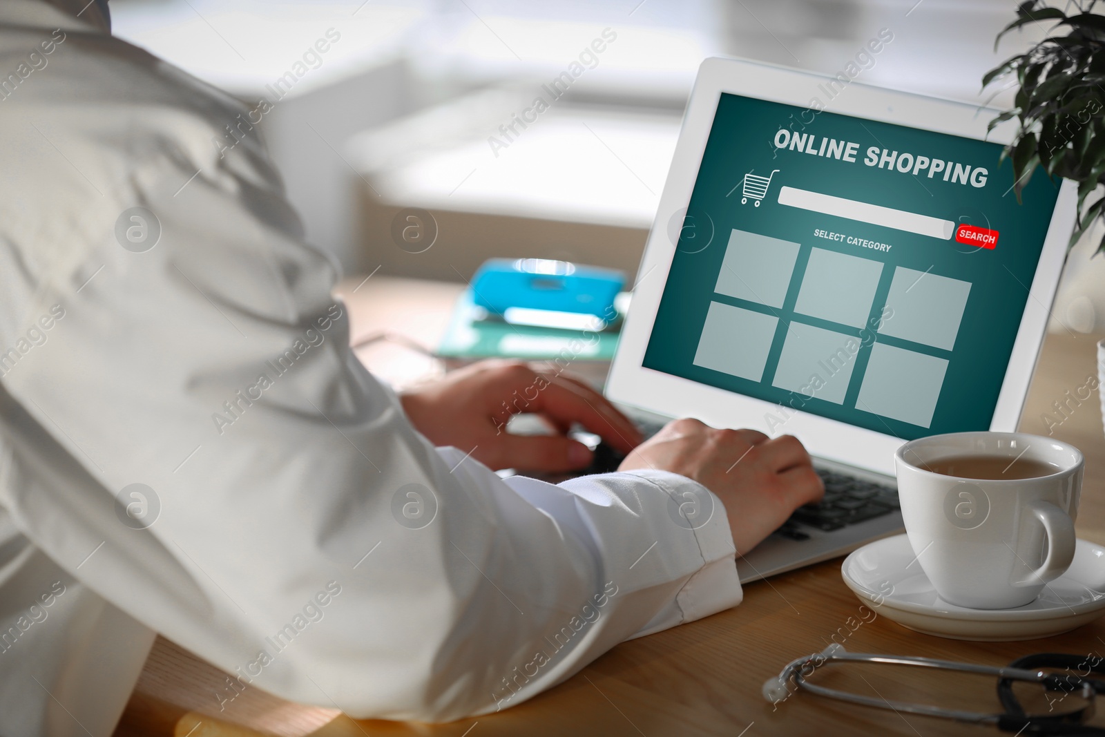 Image of Man using laptop for online shopping at wooden table, closeup