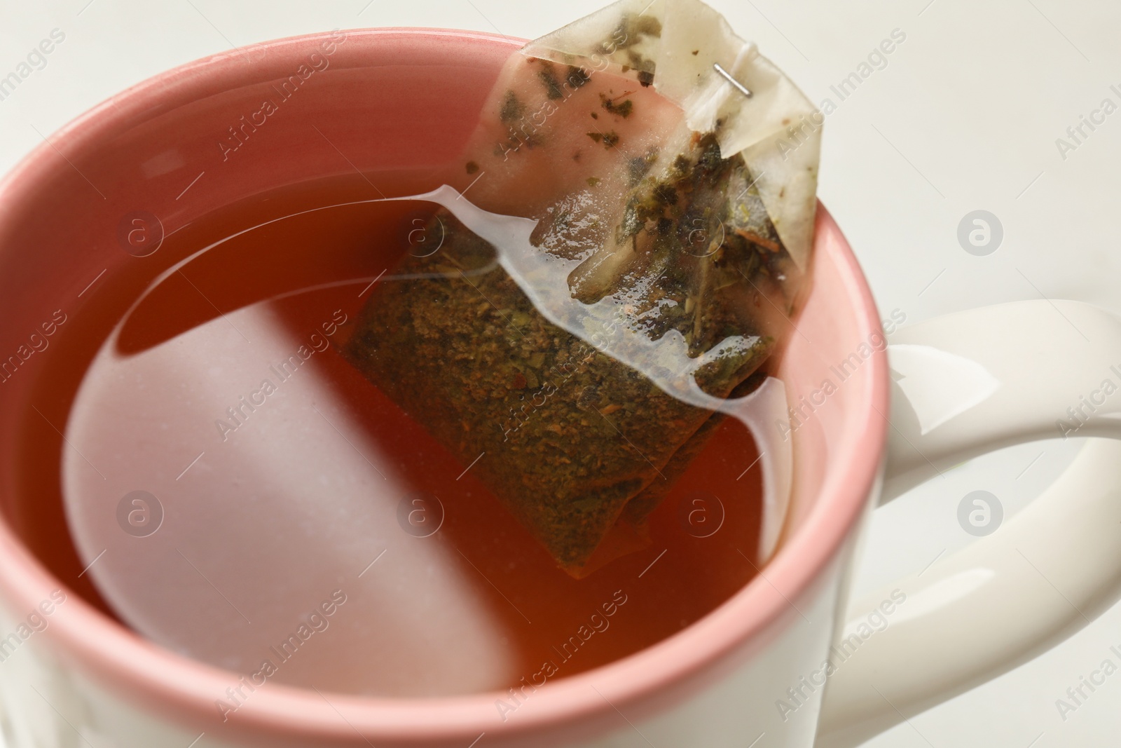 Photo of Tea bag in cup on white background, closeup