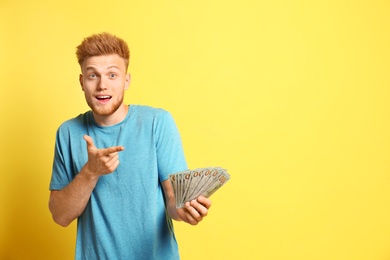 Photo of Portrait of surprised lottery winner with money on yellow background, space for text