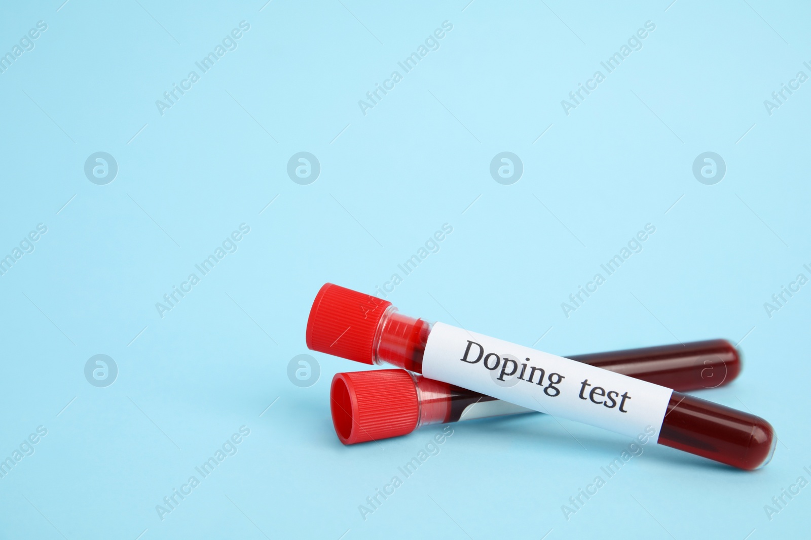 Photo of Test tubes with blood samples on light blue background, space for text. Doping control