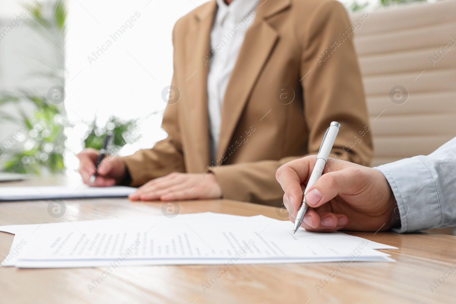 Photo of Man signing contract at table in office, closeup.