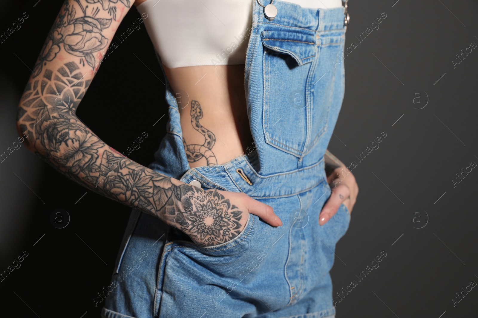 Photo of Woman with tattoos on body against black background, closeup