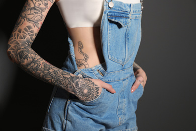 Photo of Woman with tattoos on body against black background, closeup