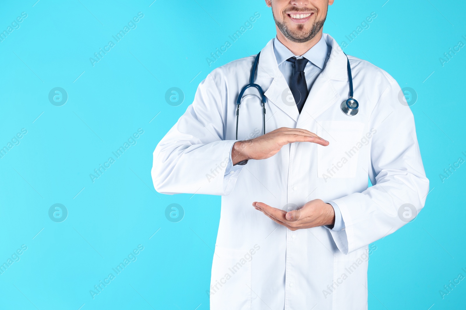 Photo of Male doctor holding something on color background, closeup with space for text