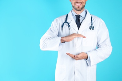 Male doctor holding something on color background, closeup with space for text