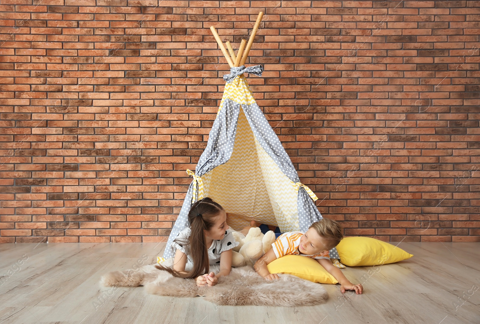 Photo of Playful little children in handmade tent indoors