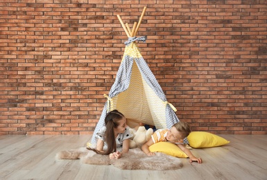 Playful little children in handmade tent indoors