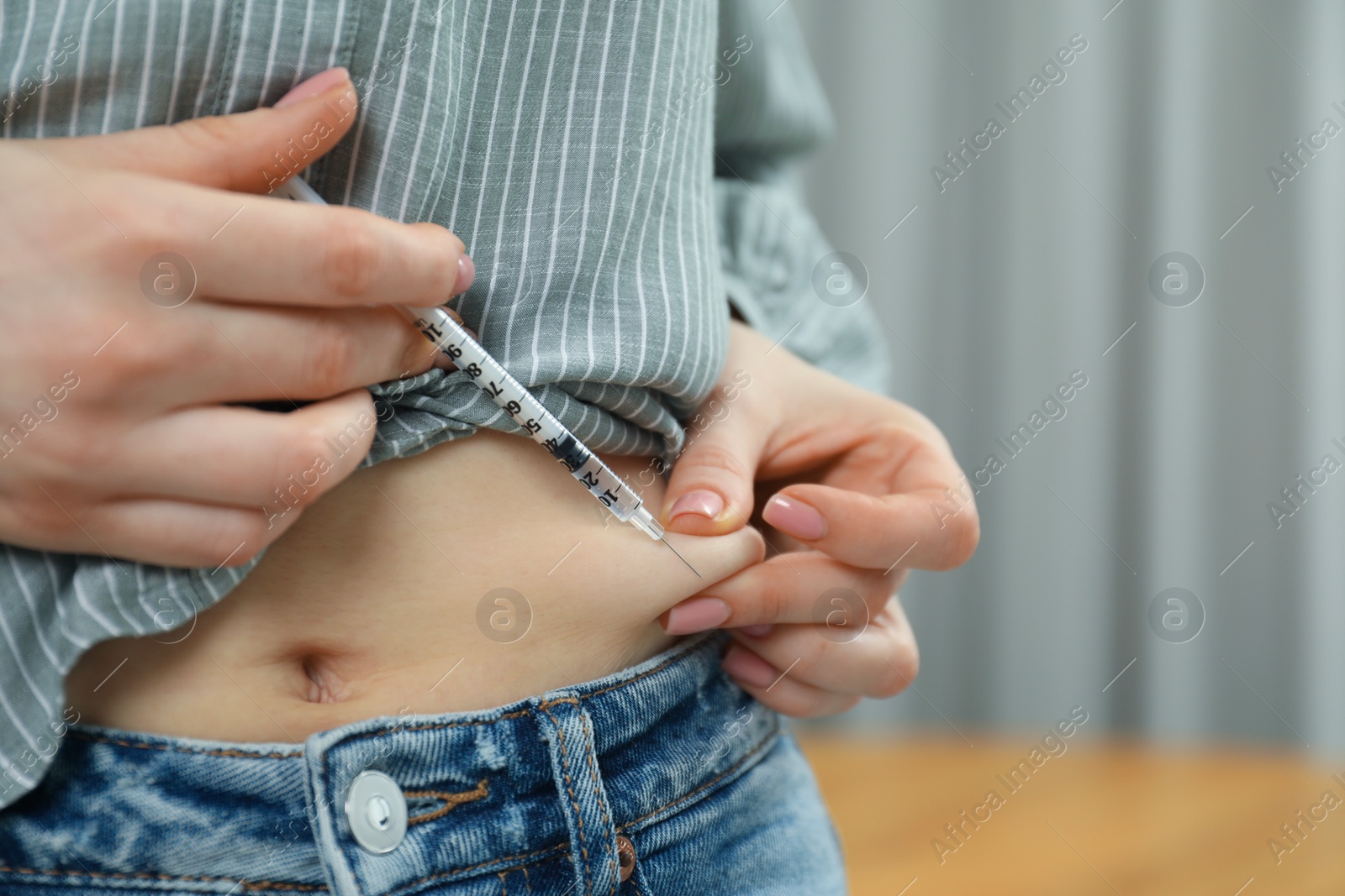 Photo of Diabetes. Woman making insulin injection into her belly indoors, closeup