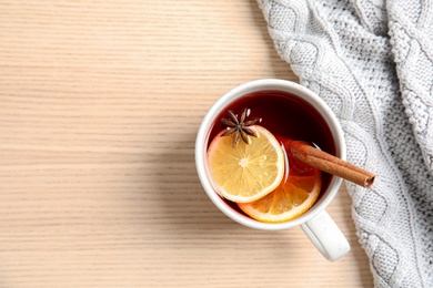 Photo of Hot winter drink in cup and warm sweater on wooden background, top view with space for text. Cozy season