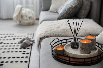 Photo of Candles and aroma reed diffuser on grey sofa, space for text