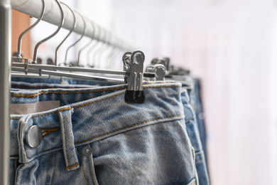 Photo of Rack with different jeans indoors, closeup view