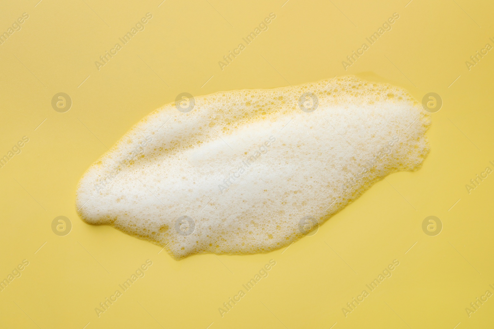 Photo of Foam with many bubbles on yellow background, above view