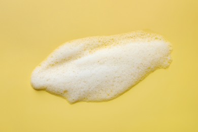 Foam with many bubbles on yellow background, above view