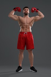 Photo of Man in boxing gloves showing muscles on grey background, low angle view