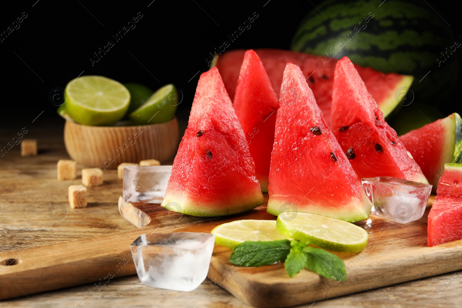 Photo of Tasty juicy watermelon, ice and lime slices on wooden table