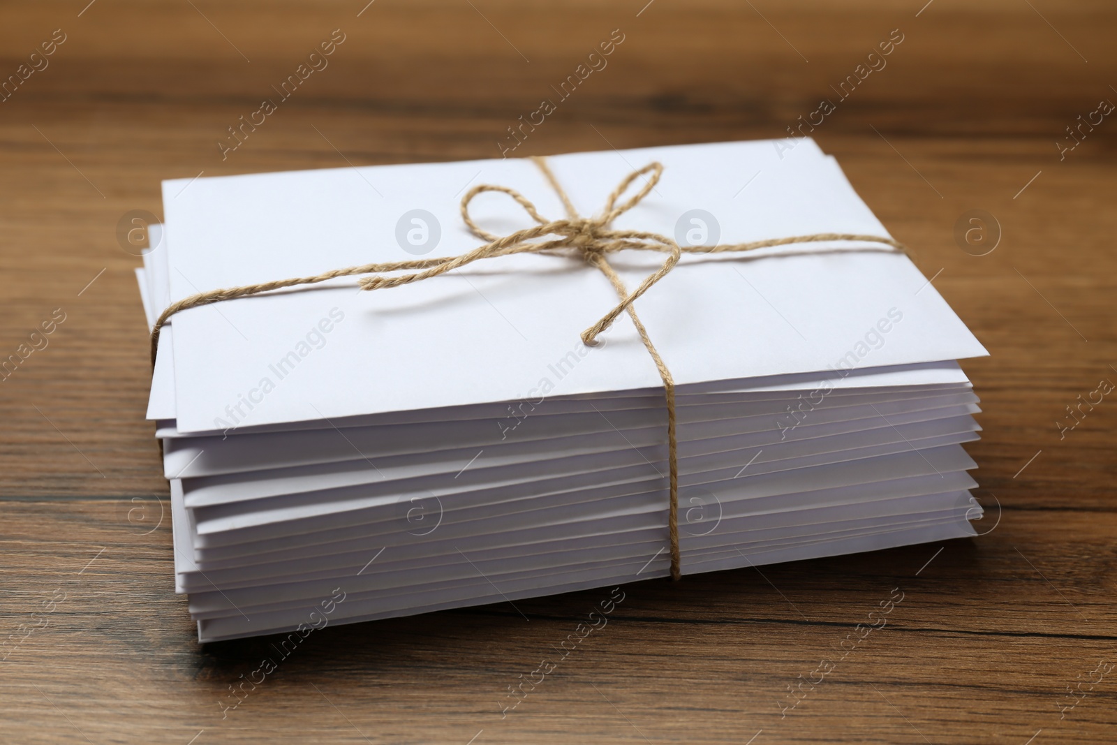 Photo of Stack of letters tied with twine on wooden table, closeup