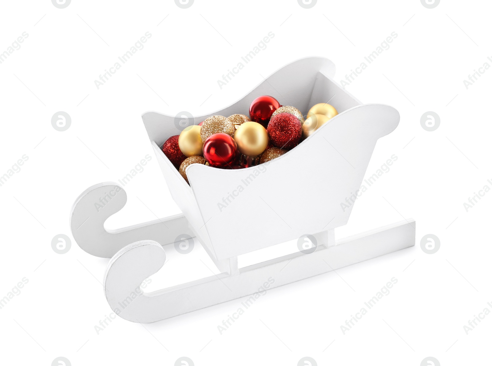 Photo of Many Christmas balls in toy wooden sleigh on white background