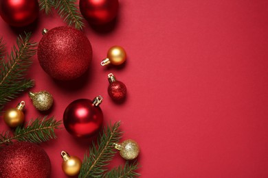 Photo of Christmas balls and fir tree branches on red background, flat lay. Space for text