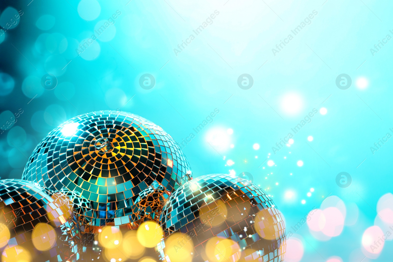 Image of Shiny disco balls on turquoise background with blurred lights, space for text. Bokeh effect