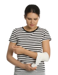 Young woman applying medical bandage onto arm against white background