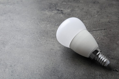 Photo of New modern lamp bulb on grey stone surface. Space for text