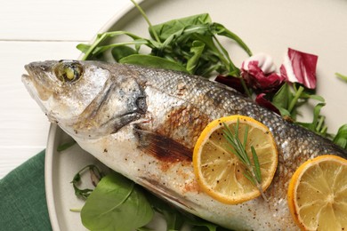 Photo of Baked fish with spinach and lemon on white wooden table, top view