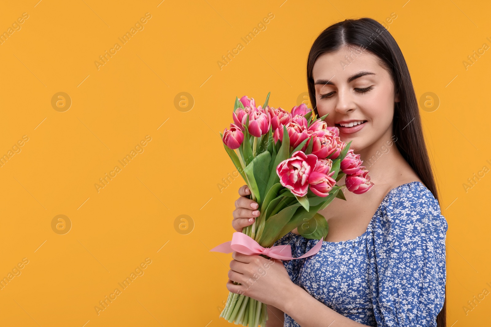 Photo of Happy young woman with beautiful bouquet on orange background. Space for text