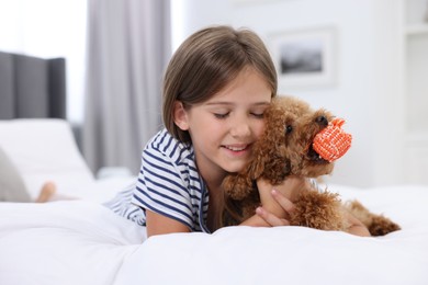 Little child hugging cute puppy on bed at home. Lovely pet