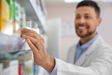 Professional pharmacist near shelves with merchandise in drugstore, focus on hand
